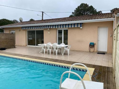 une maison avec une table et des chaises à côté d'une piscine dans l'établissement Villa proche océan à Montalivet les Bains, à Vendays-Montalivet