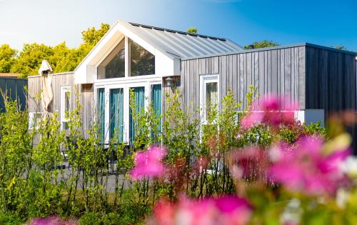 a small house in a garden with flowers at Camping Hotel Renesse in Renesse