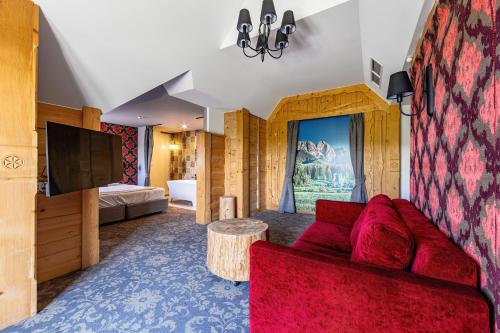 a living room with a red couch and a television at Hotel Gazdówka Spa in Osielsko