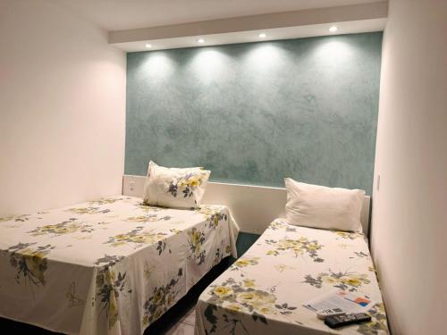 a small room with two beds and a green wall at Ilha Bela Pousada in Maceió