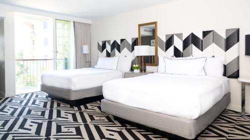 a bedroom with two beds and a large window at Chamberlain West Hollywood in Los Angeles