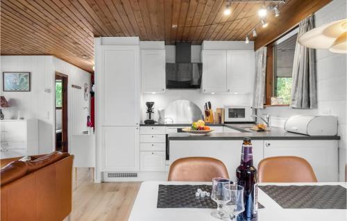 a kitchen with white cabinets and a table with chairs at Holiday Home Alfedalen in Kalundborg