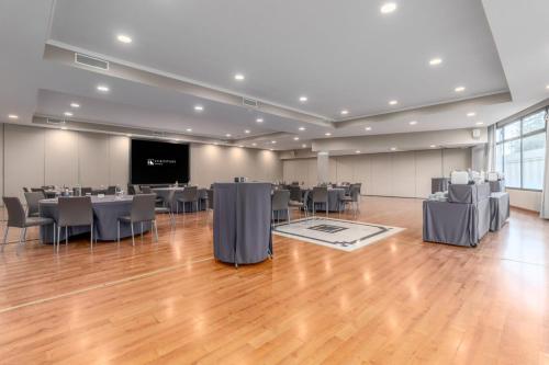 a large room with tables and chairs and a projection screen at Eurostars Madrid Foro in Tres Cantos