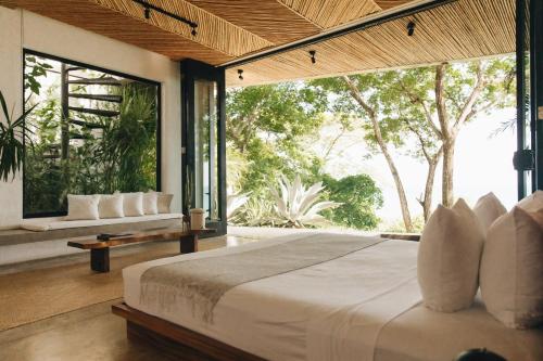 a bedroom with a large bed and large windows at Mint Santa Teresa - Adults only in Santa Teresa Beach