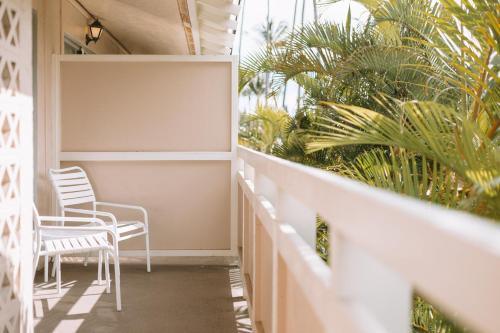 a balcony with two chairs and palm trees at Plantation Hale Suites in Kapaa