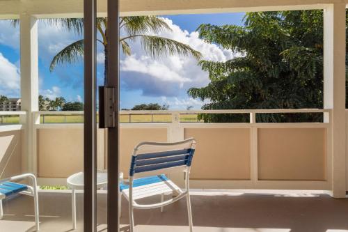 a chair and a table on a balcony with a palm tree at Plantation Hale Suites in Kapaa