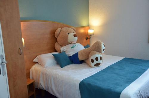 a teddy bear sitting on top of a bed at BRIT HOTEL Caen Hérouville in Hérouville-Saint-Clair