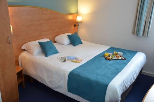 a hotel room with a bed with a tray of food on it at BRIT HOTEL Caen Hérouville in Hérouville-Saint-Clair