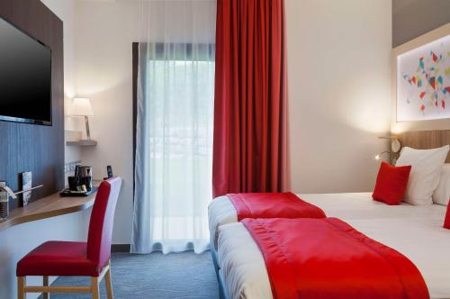 a hotel room with a bed and a red curtain at Brit Hotel Privilège Figeac in Figeac