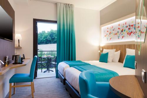 a hotel room with a bed and a balcony at Brit Hotel Privil&egrave;ge Figeac in Figeac