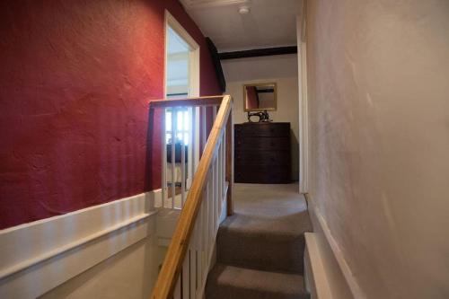 una escalera en una habitación con una pared roja en Perfect cottage retreat near the Brecon Beacons, en Llanwrda