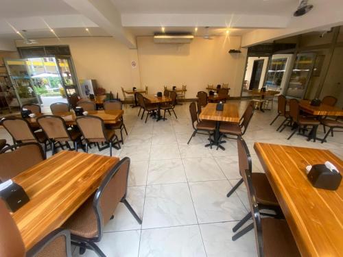 an empty restaurant with wooden tables and chairs at Hotel California Pacific Palm in Escuintla