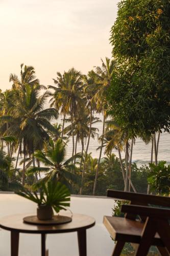 a patio with palm trees and a table and a view of the ocean at Diviya Villa - Madiha Hill in Madihe East