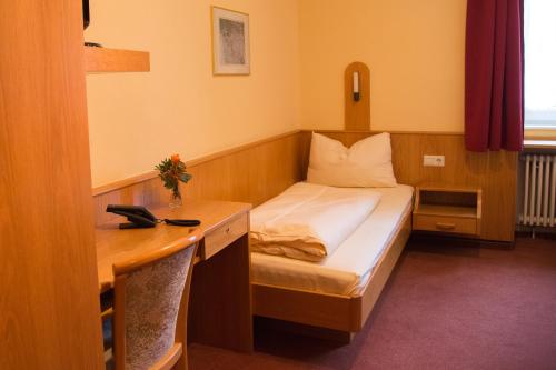 a small room with a bed and a desk at Hotel Restaurant Löwen in Zell im Wiesental