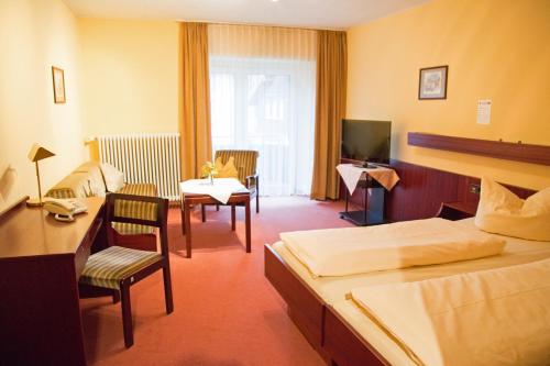 a hotel room with a bed and a desk and chairs at Hotel Restaurant Löwen in Zell im Wiesental
