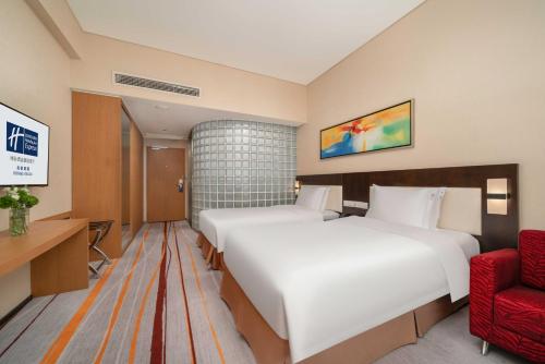 a hotel room with two beds and a red chair at Holiday Inn Express Chengdu Gulou-Tianfu Square Chunxi Road Branch in Chengdu