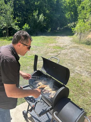 a man is cooking food on a grill at Holiday house in nature in Keda