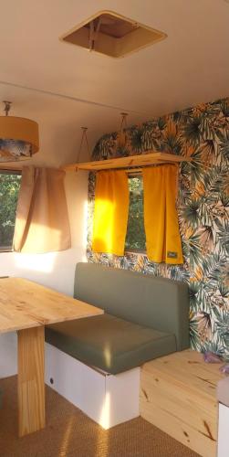 une table et un banc dans une remorque avec fenêtres dans l'établissement La Caravane d'Alon, à Magrie