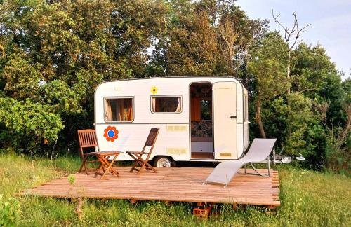 un camping-car avec deux chaises et une terrasse en bois dans l'établissement La Caravane d'Alon, à Magrie