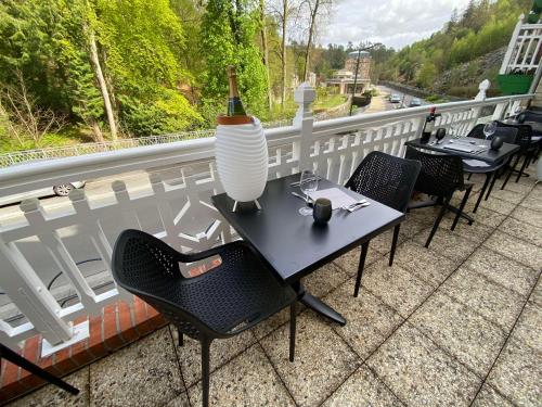 a table with chairs and a vase on a balcony at BRIT HOTEL & SPA Le Roc au Chien in Bagnoles de l'Orne