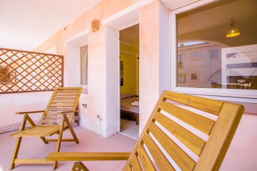 a balcony with two wooden chairs and a window at Porto Cervo Two-Levels Apt with Balconies and Parking in Porto Cervo