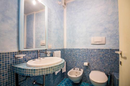 a blue tiled bathroom with a sink and a toilet at Porto Cervo Two-Levels Apt with Balconies and Parking in Porto Cervo