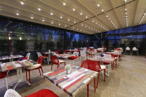 een restaurant met tafels en stoelen en een groot raam bij Buca Residence Hotel in Izmir