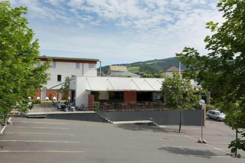 a building in a parking lot with a building at Brit Hotel Marvejols in Marvejols