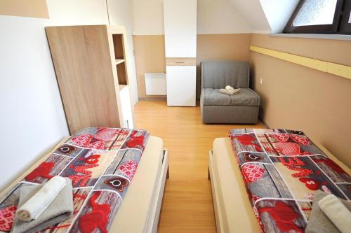 two beds in a small room with a chair at Aparthouse SUPREME with Terme Catez Swimming Pools Tickets in Čatež ob Savi