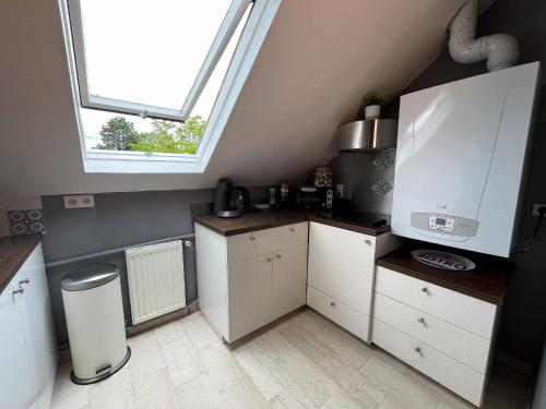 a kitchen with white cabinets and a large window at Appartement les Glaneuses (2D) 4 pers. Barbizon in Barbizon