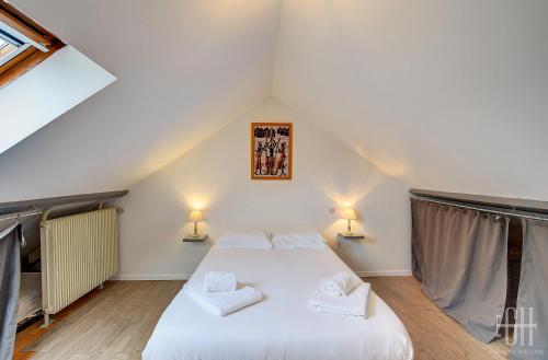 une chambre avec un lit blanc dans un grenier dans l'établissement Loéva - Maison de famille, à Tours