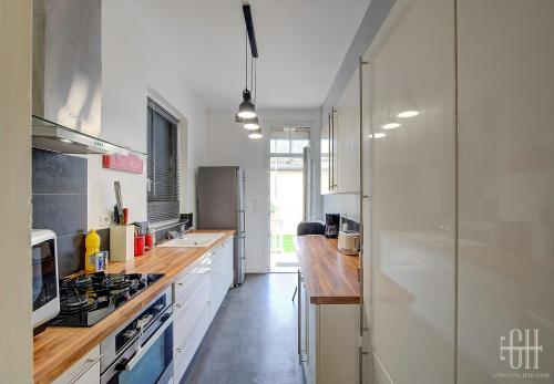 une cuisine avec des armoires blanches et un comptoir en bois dans l'établissement Loéva - Maison de famille, à Tours