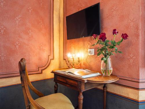 a table with a vase of flowers on it with a vase of red at PALAZZO CHERCHI in Dorgali