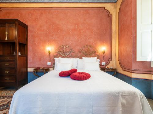 two red pillows on a white bed in a room at PALAZZO CHERCHI in Dorgali