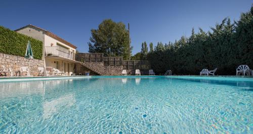 une grande piscine d'eau bleue en face d'un bâtiment dans l'établissement Auberge de l'Escargot d'Or, à Dieulefit