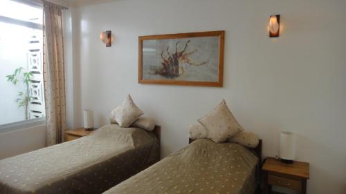 a bedroom with two beds and a picture on the wall at Argonauta Boracay Apartment Suites and Villas in Boracay