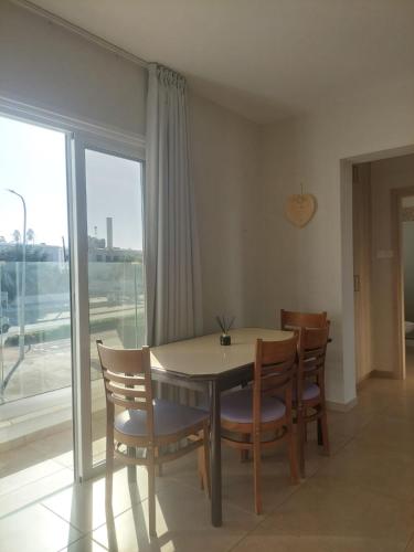 a dining room with a table and chairs and a window at Proteas Mare Suites in Protaras