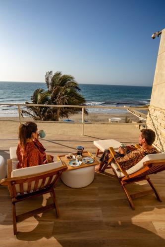 two people sitting in lawn chairs on the beach at DCO Suites Lounge & Spa in Máncora
