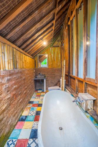 a bath tub in a room with a tiled floor at Ubud Sawah Scenery Villa and Homestay in Tegalalang