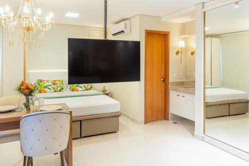 a dining room with a dining table and a large tv at PALMAS EXPERIENCE - FLAT ACONCHEGANTE no centro in Palmas