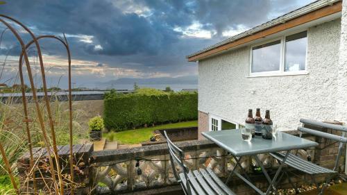a table and chairs on a balcony with bottles of wine at Eryri in Beaumaris