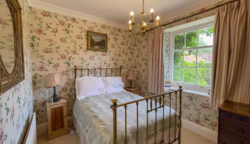 a bedroom with a bed with floral wallpaper at West Compton Manor in Dorchester