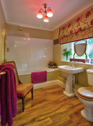 a bathroom with a tub and a sink and a toilet at West Compton Manor in Dorchester
