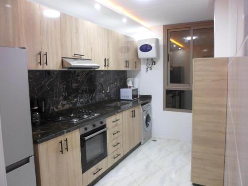 a kitchen with wooden cabinets and a stove top oven at Alliance Appart plage -Mehdia in Plage de Mehdia