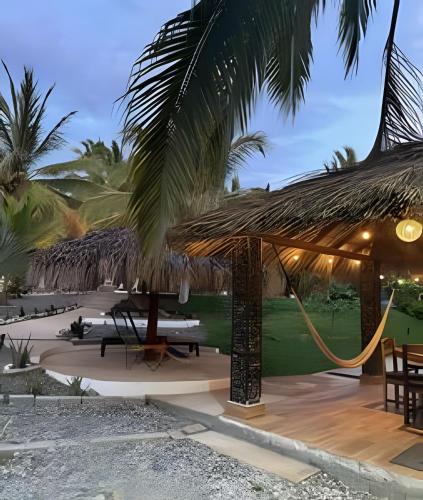 a resort with a hammock and a resort with palm trees at Casa Las Palmas Playa La Saladita in Zihuatanejo