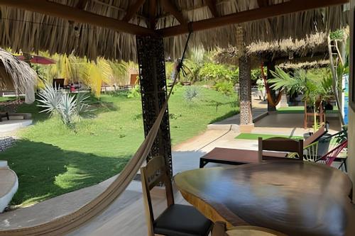 a hammock in a restaurant with a view of a yard at Casa Las Palmas Playa La Saladita in Zihuatanejo