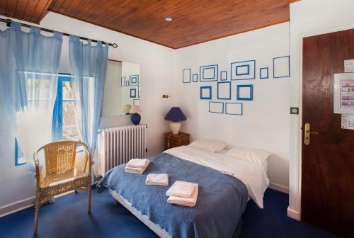 een slaapkamer met een bed, een stoel en een raam bij Auberge de l'Escargot d'Or in Dieulefit