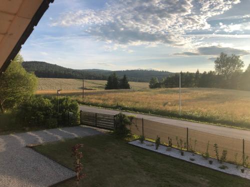 a view of a field and a road with a bench at Przylesie Domki in Wysoczany