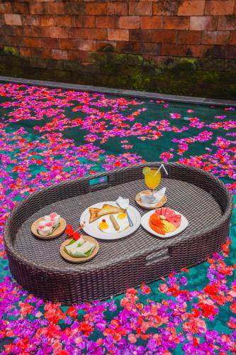 a table with plates of food and a drink and flowers at Ubud Sawah Scenery Villa and Homestay in Tegalalang
