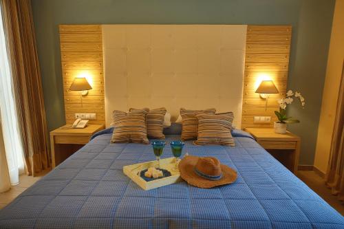 a bed with a tray with a hat and two glasses at Dolphin Bay Seaside Resort & Suites in Galissas